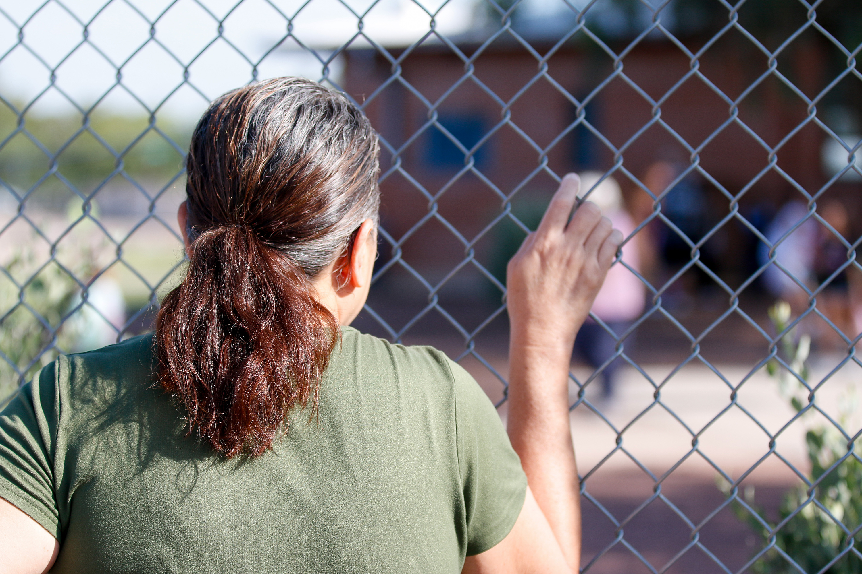 A mom looks through the fence on the second day of school