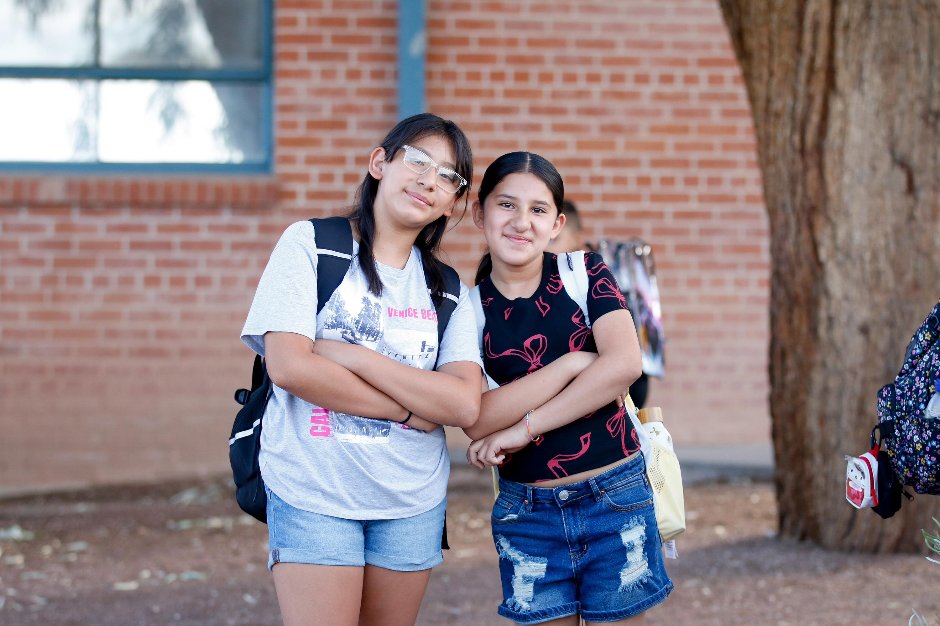 Two girls smile with their arms crossed