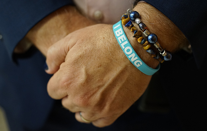 A close up of hands with a bracelet saying I Belong