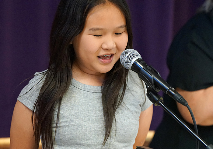 A young girl speaks into a microphone