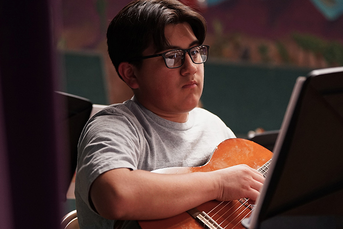 A boy in glasses plays guitar