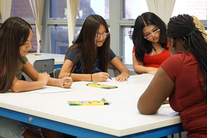 Four girls draw at a table