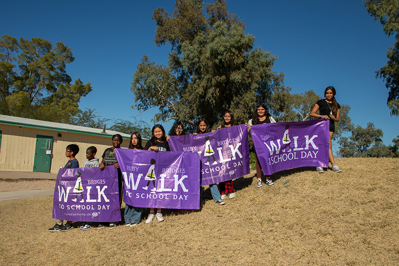 Students hold up four purple Ruby Bridges Walk to School Day banners