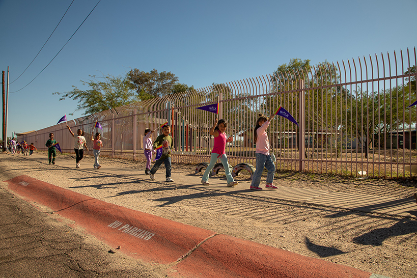 Students walk around the outside of the school with their purple Ruby Bridges pennants