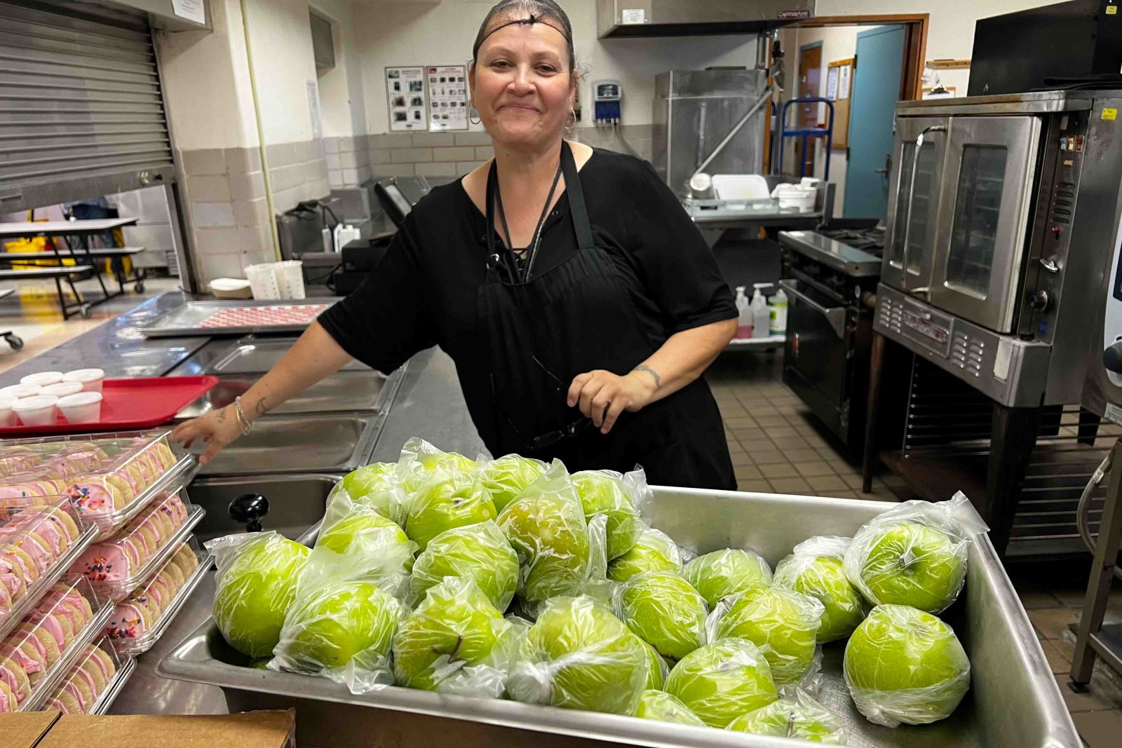 A Food Services worker serves lunch with a smile on the first day of school