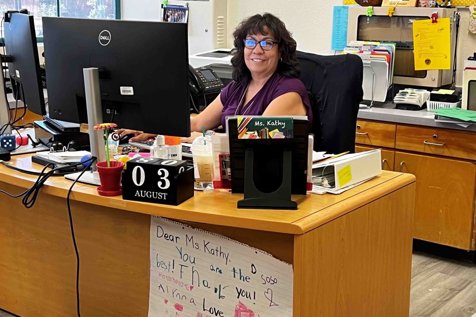 A Pueblo Gardens teacher smiles at her desk on the first day of school